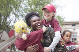 Lapset ympäröivät ja halaavat ohjaajaa